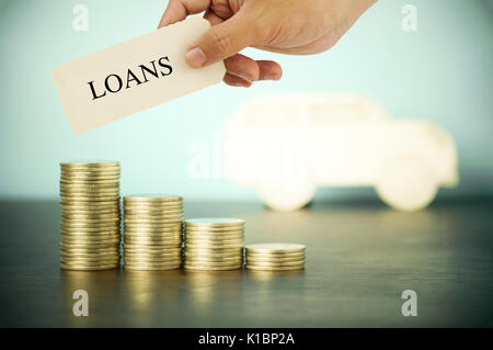 hand hokding and show loans sign on pile of money coins , concept in buying, selling and car finance Stock Photo