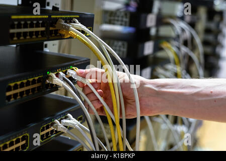 Hand with rj45 cable and network equipment on background Stock Photo