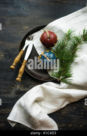 Table setting for festive Christmas dinner on dark wooden table with vintage plates and silverware Stock Photo