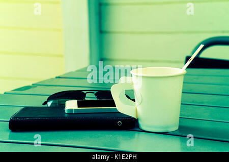 Mobile phone with paper cup of coffee on table Stock Photo