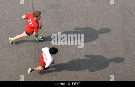 Two people run along the bank of Spree river in Berlin, Germany, 26 August 2017. Photo: Ralf Hirschberger/dpa Stock Photo