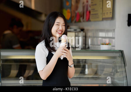 Brighton, UK. 27th Aug, 2017. A young woman enjoys an ice cream on Brighton seafront in the beautiful hot sunny weather today as temperatures are expected to reach as high as 28 degrees over the bank weekend which is a record for August Credit: Simon Dack/Alamy Live News Stock Photo