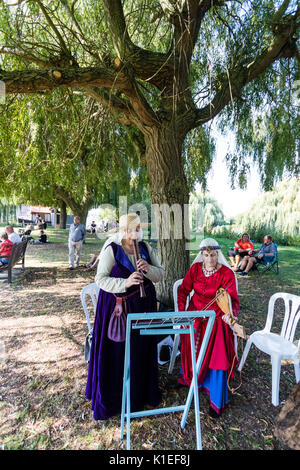 England, Sandwich. Living History players, two women, in medieval costume, standing under a tree playing recorder and rebec, the fore-runner to the violin. Stock Photo