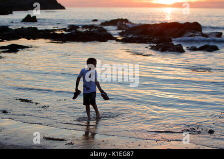 Fistral Beach, Newquay, Cornwall, UK. 27th Aug, 2017. A warm cloudless day gives way to a beautiful sunset.  A boy runs in and out of the ocean as sunset approaches. Credit: Nicholas Burningham/Alamy Live News Stock Photo