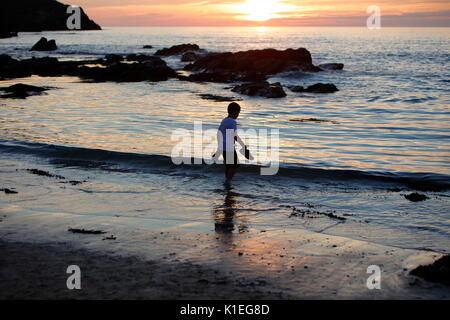 Fistral Beach, Newquay, Cornwall, UK. 27th Aug, 2017. A warm cloudless day gives way to a beautiful sunset.  A boy runs in and out of the ocean as sunset approaches. Credit: Nicholas Burningham/Alamy Live News Stock Photo