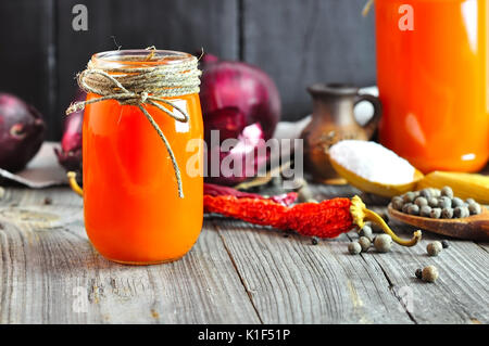 Fresh detox carrot juice in glass bottles on a gray stone