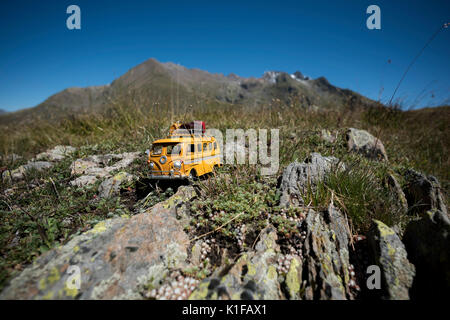 Hippies Minivan (RV van toy) on a rock, with mountains in the background, French Alps, Isere, France Stock Photo