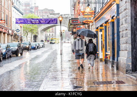 Quebec City, Canada - May 31, 2017: Old town street Saint-Jean during heavy rain with drops and wet road with couple walking Stock Photo