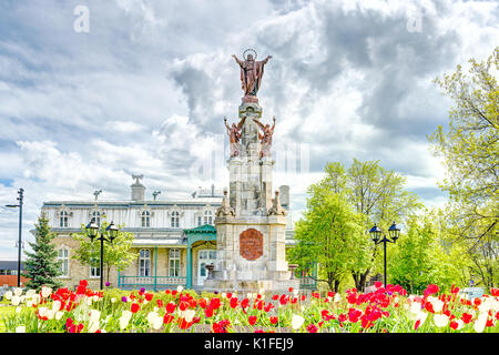 Saint-Augustin-de-Desmaures, Canada - May 29, 2017: Parish of Sainte Augustin in small town on Chemin du Roy with statue of Jesus Christ and tulips Stock Photo