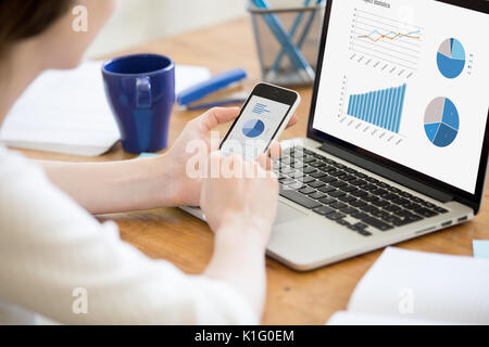 Businesswoman holding smartphone, working with laptop, using cro Stock Photo