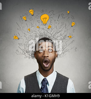 Young man with many idea light bulbs above head looking up isolated on gray wall background.
