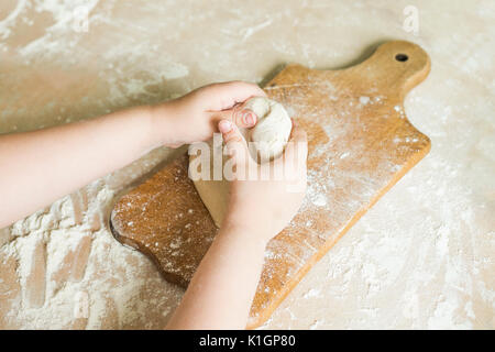 Side view shoot of children's hands make dough on the wooden board. Learning in kindergarten Stock Photo