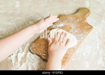 Side view shoot of children's hands make dough on the wooden board. Learning in kindergarten Stock Photo