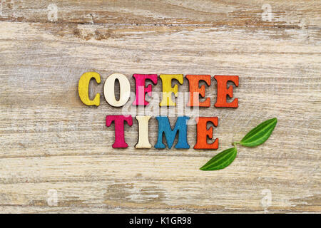 Coffee time written with colorful wooden letters and two green leaves Stock Photo