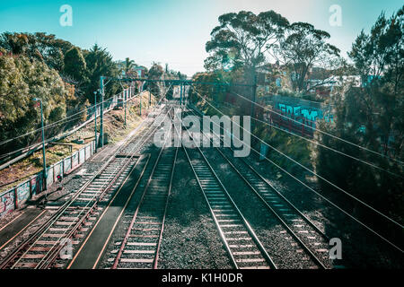 Melbourne, Australia - July 29, 2017: rail tracks and power lines vanishing in the distance on bright summer day Stock Photo