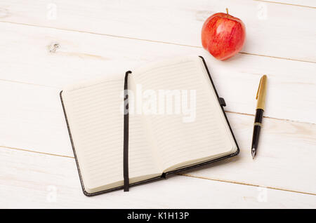 Diary, apple and pen on rustic wooden table Stock Photo