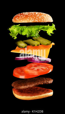 Big tasty home made burger with flying ingredients on black background. Stock Photo