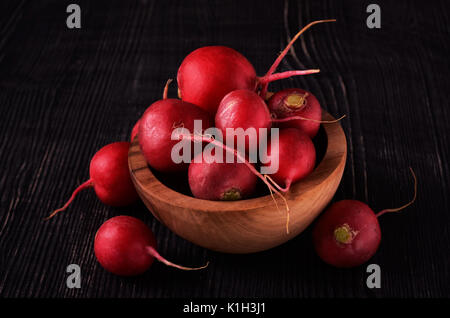 Organic red radish on dark in wood bowl wooden background Stock Photo