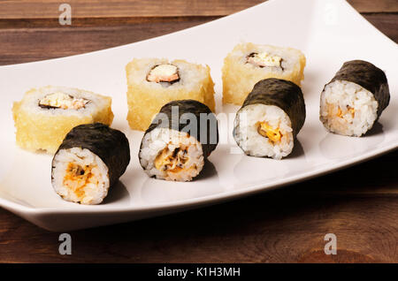 Sushi rolls in a white plate on a wooden table Stock Photo