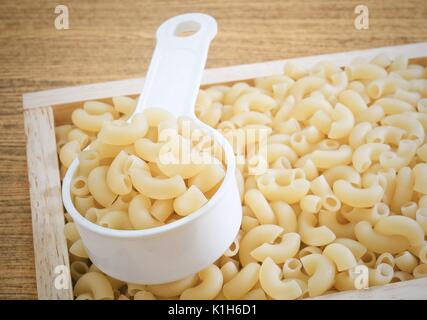 Food and Cuisine, Uncooked and Dried Elbow Macaroni or Gomiti Pasta in Plastic Measuring Cup. Stock Photo