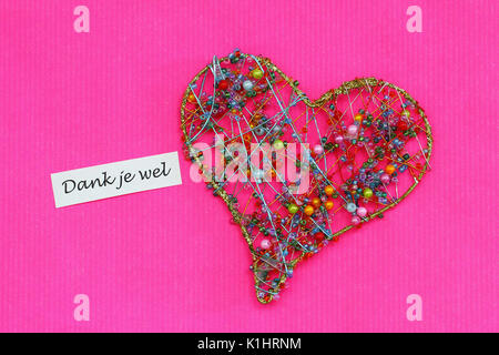 Dank je wel (thank you in Dutch) card with heart on vivid pink surface Stock Photo