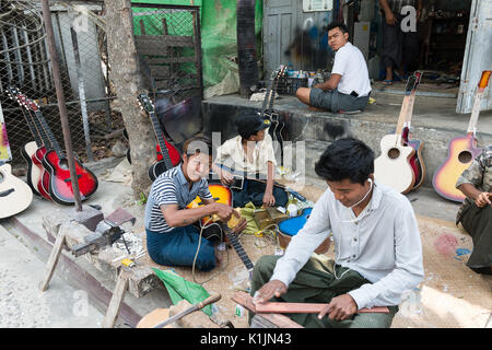 A group of young men make acoustic guitars in an outdoor workshop in Mandalay, Myanmar.
