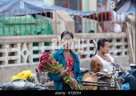 Local woman holds a bunch of flowers at the local market in Hpa-an, Kayin State, Myanmar. Stock Photo