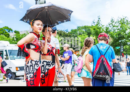 Washington DC, USA - July 3, 2017: Tourists waiting to cross street road on national mall with closeup of chinese girls holding umbrella Stock Photo