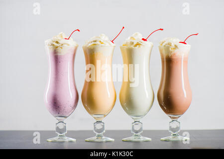 Row of various sweet milkshakes with cherries in glasses on the table Stock Photo