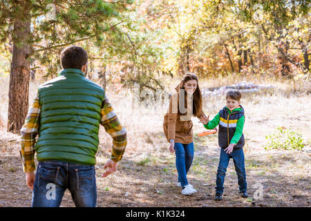 Happy family playing with frisbee and having fun in autumn park Stock Photo