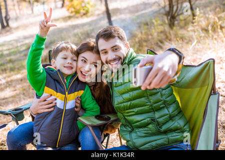 Happy smiling family at picnic having fun and taking selfie in autumn park Stock Photo