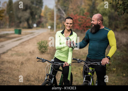 Couple of cyclists resting during cycling journey in autumn park Stock Photo