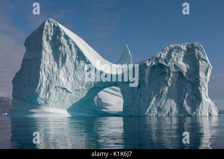 Greenland, Eastern Greenland, Scoresbysund aka Scoresby Sund, Bear Island aka Bjorne Oer. Huge iceberg with hole around the Bear Islands. Stock Photo