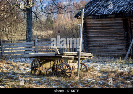 An old wooden cart stands on snow-covered grass. Stock Photo