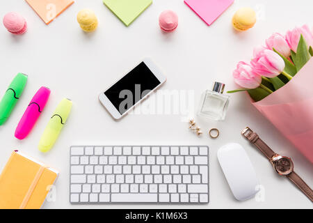 Top view of smartphone, keyboard with computer mouse, bouquet of pink tulips and office supplies isolated on white Stock Photo