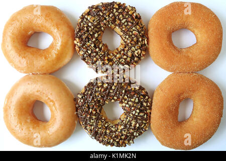 Top view of six doughnuts, two sugar-glazed, two chocolate with nuts and two cinnamon sugar Stock Photo