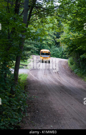 yellow school bus driving down a rural road Stock Photo