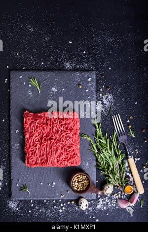 Ground meat, burger patty preparation, seasoning, spices and herbs. Above view, copy space.