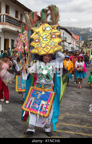 June 18, 2017 Pujili, Ecuador: indigenous kichwa man dancing in the street in traditional dress balancing a large display on his head at Corpus Christ Stock Photo