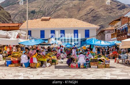 Local Peru women in colorful traditional clothing sell vegetables at the Sunday Market in Pisac, Peru, Sacred Valley, South America. Stock Photo