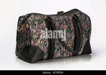 Close Up Shot Of A Unisex Duffle Bag With Multicolor  Floral Pattern and Leather trim And Gold Hardware Isolated On White Background Stock Photo