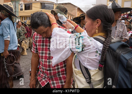 July 24, 2017 Cotacachi, Ecuador: indigenous kichwa woman pouring water over a man's head on the hot day of Inti Raymi celebration Stock Photo