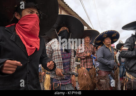 July 24, 2017 Cotacachi, Ecuador: indigenous men in costumes some with face covered dancing on the street at Inti Raymi Stock Photo