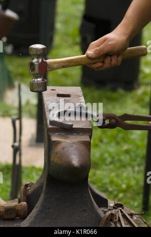 Farrier producing horseshoes in the traditional method on an anvil. Stock Photo