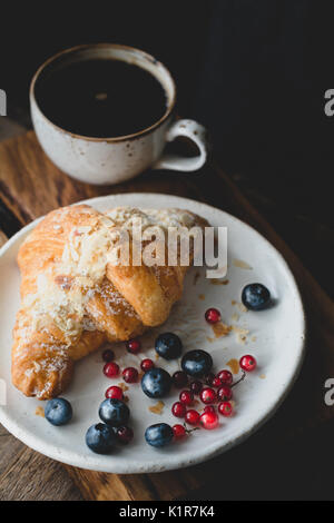 Almond croissant, berries and cup of coffee. Closeup view, toned image Stock Photo
