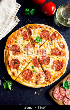 Pepperoni Pizza with ingredients - Fresh homemade pizza with pepperoni, cheese and tomato sauce and ingredients on rustic black stone background with  Stock Photo