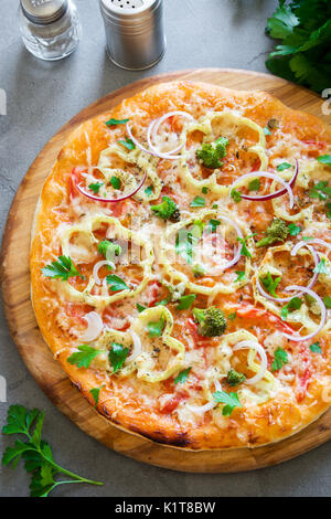 Vegetarian Pizza on rustic concrete background. Italian Pizza with Vegetables and Cheese close up. Stock Photo