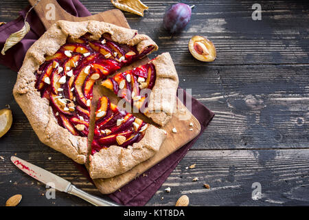 Plum Galette. Healthy homemade wholegrain fruit pie (galette) with plums, almonds and brown sugar, vegan vegetarian autumn dessert food. Stock Photo