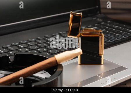 Luxurious gold lighter and cigar on laptop background. As a background. splash screen Stock Photo