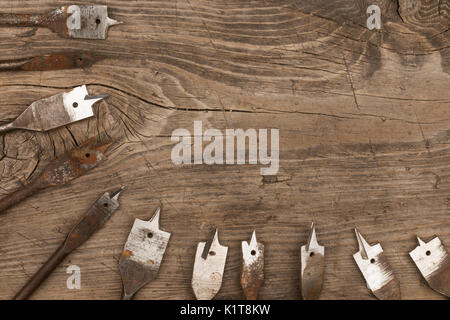 Old metal spade bits for drilling wood lie wooden background. View from above Stock Photo